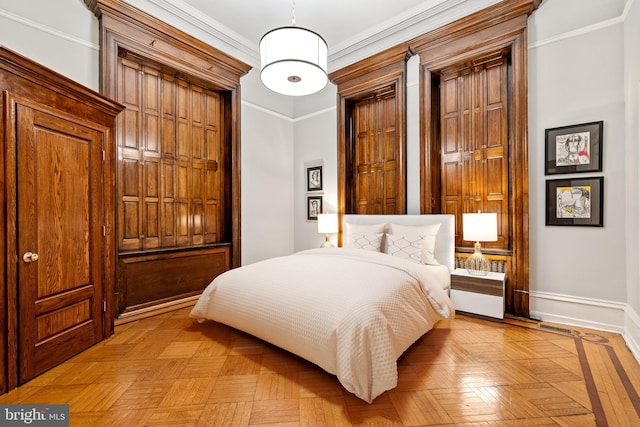 bedroom with ornamental molding and light parquet flooring