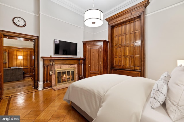 bedroom with a fireplace, light parquet flooring, and crown molding