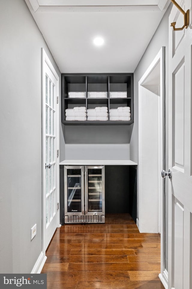 bar with wine cooler and dark wood-type flooring