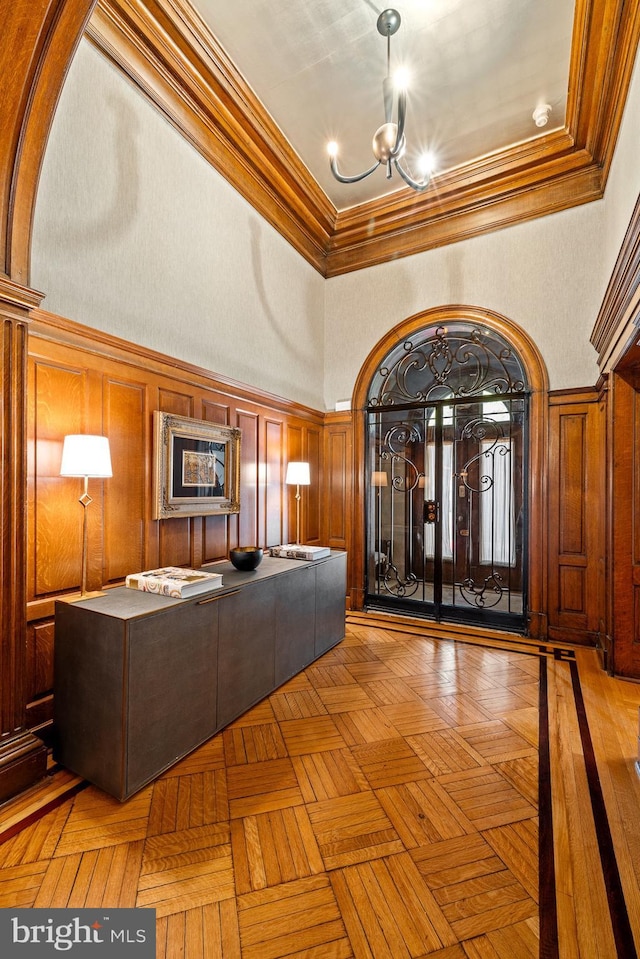 interior space with parquet flooring, a towering ceiling, a chandelier, and crown molding