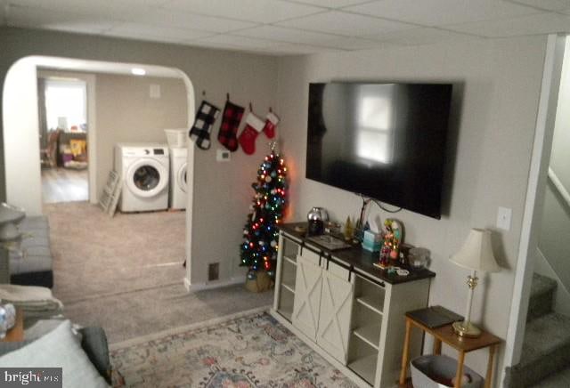 living room featuring carpet flooring, washing machine and dryer, and a drop ceiling