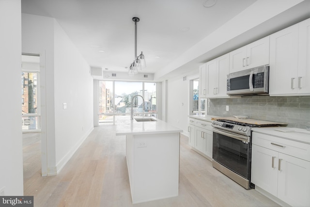 kitchen with white cabinets, light hardwood / wood-style floors, and appliances with stainless steel finishes