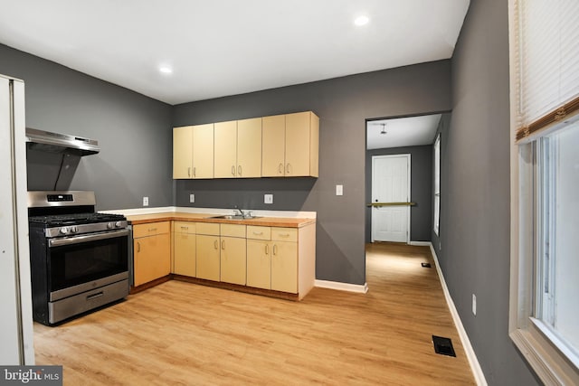 kitchen with ventilation hood, gas stove, light wood-type flooring, and sink