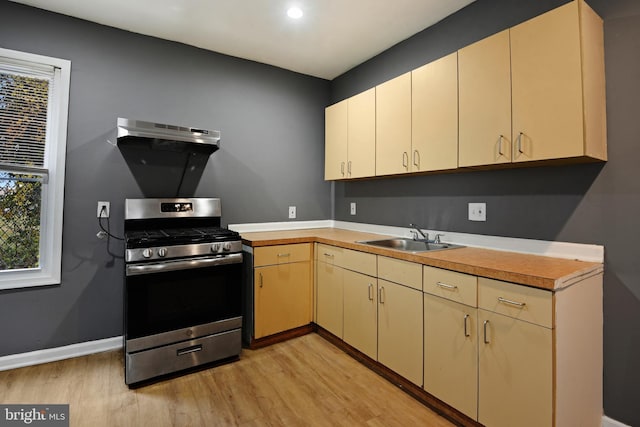 kitchen with sink, light hardwood / wood-style floors, extractor fan, and stainless steel gas range