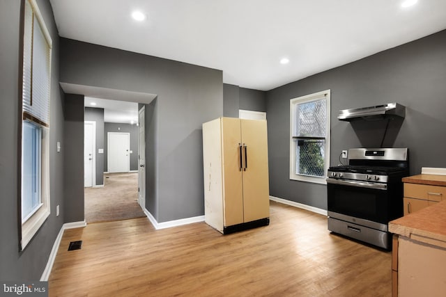 kitchen featuring stainless steel gas stove, range hood, and light wood-type flooring