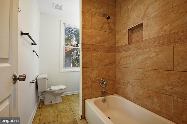 bathroom with tile patterned flooring, tiled shower / bath combo, and toilet