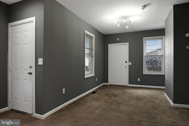 entrance foyer with dark carpet and an inviting chandelier