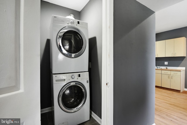 laundry area featuring stacked washer and clothes dryer and hardwood / wood-style flooring