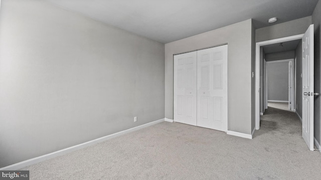 unfurnished bedroom with a closet and light colored carpet