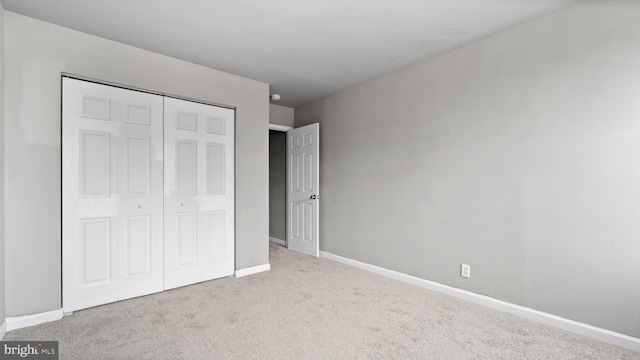 unfurnished bedroom featuring a closet and light colored carpet