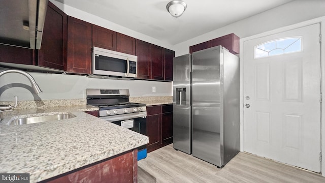 kitchen featuring light hardwood / wood-style floors, light stone counters, sink, and appliances with stainless steel finishes