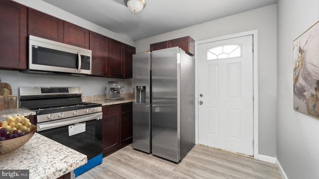 kitchen with light stone countertops, stainless steel appliances, and light hardwood / wood-style floors