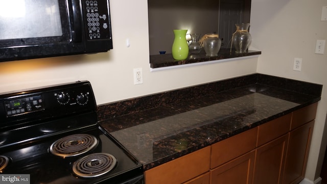 kitchen featuring dark stone countertops and black appliances