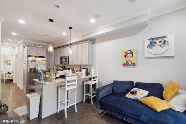 kitchen with dark hardwood / wood-style floors, kitchen peninsula, pendant lighting, appliances with stainless steel finishes, and ornamental molding