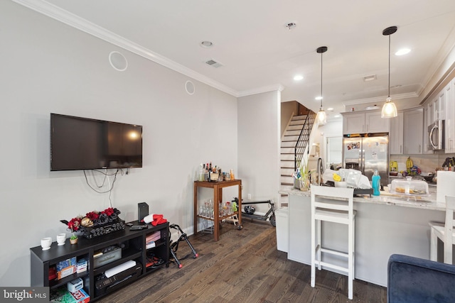 kitchen with light stone counters, dark hardwood / wood-style floors, pendant lighting, appliances with stainless steel finishes, and ornamental molding