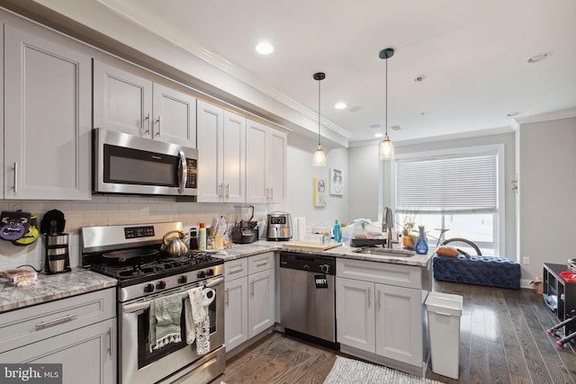 kitchen featuring light stone countertops, appliances with stainless steel finishes, sink, decorative light fixtures, and dark hardwood / wood-style floors