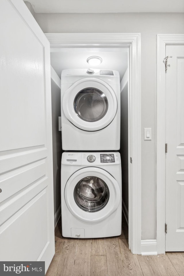 clothes washing area with stacked washer / dryer and light hardwood / wood-style flooring