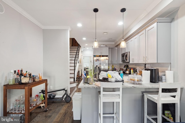 kitchen featuring pendant lighting, a breakfast bar, crown molding, dark hardwood / wood-style flooring, and stainless steel appliances