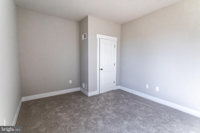 spare room with dark colored carpet