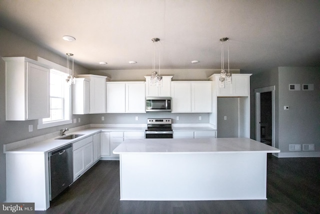 kitchen featuring white cabinetry, a center island, decorative light fixtures, and appliances with stainless steel finishes