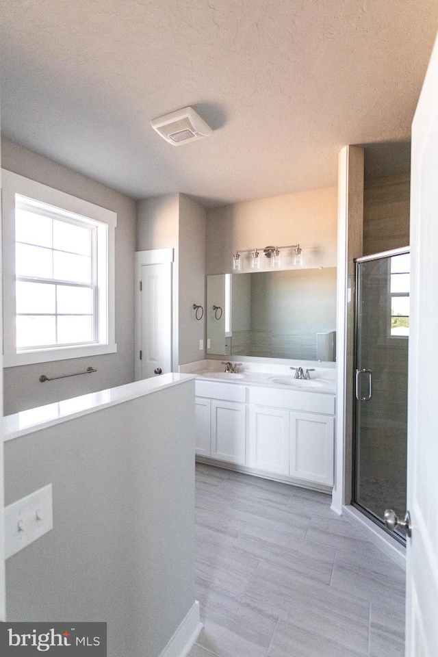 bathroom featuring a textured ceiling, vanity, and walk in shower