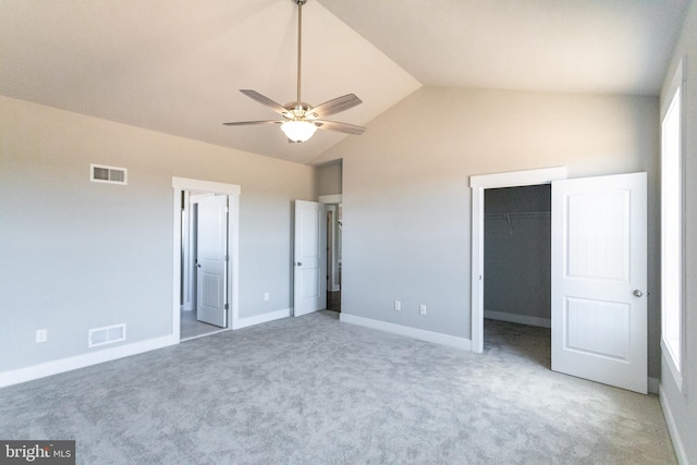 unfurnished bedroom featuring a walk in closet, vaulted ceiling, ceiling fan, carpet floors, and a closet