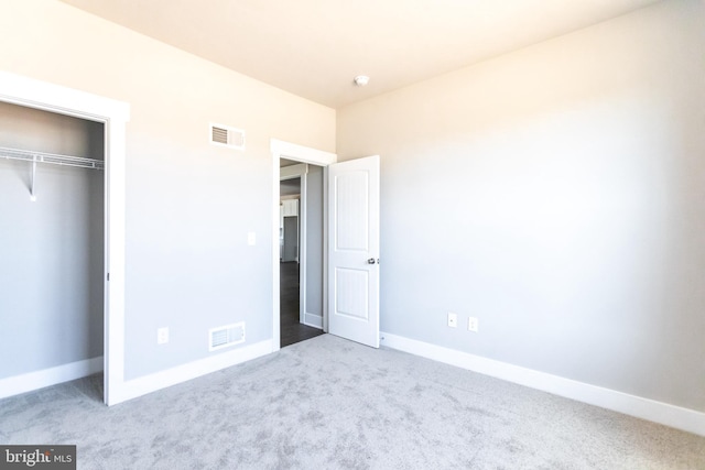 unfurnished bedroom featuring a closet and light colored carpet