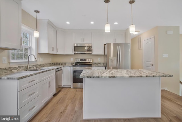 kitchen featuring hanging light fixtures, appliances with stainless steel finishes, white cabinetry, and sink