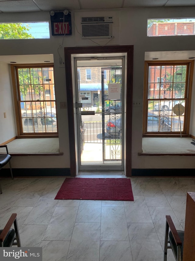 doorway to outside with light tile patterned flooring, a healthy amount of sunlight, and a wall mounted air conditioner