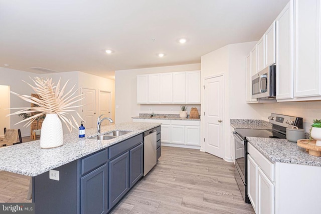 kitchen with sink, white cabinets, stainless steel appliances, and a center island with sink