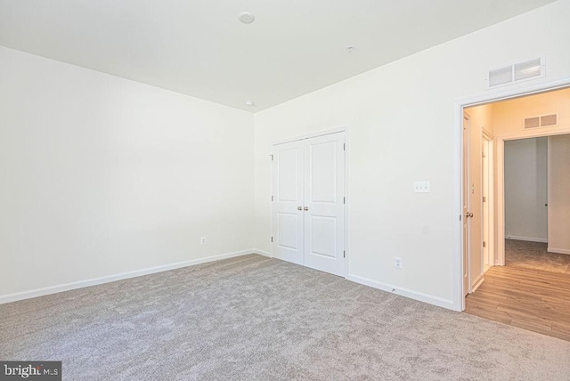 unfurnished bedroom with light colored carpet and a closet