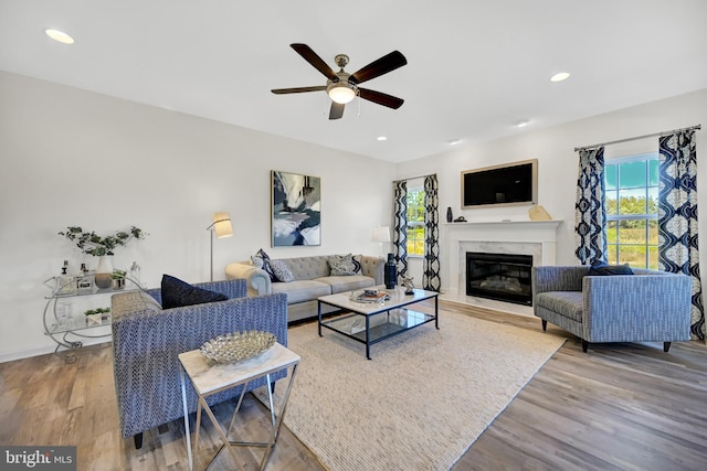 living room with a fireplace, wood-type flooring, and ceiling fan