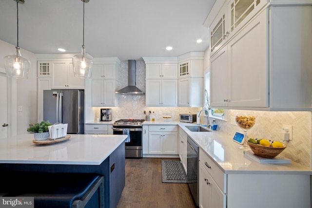 kitchen featuring decorative light fixtures, stainless steel appliances, white cabinetry, and wall chimney exhaust hood