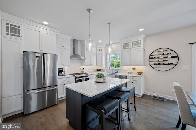 kitchen featuring stainless steel appliances, wall chimney range hood, a kitchen island, dark hardwood / wood-style floors, and white cabinets