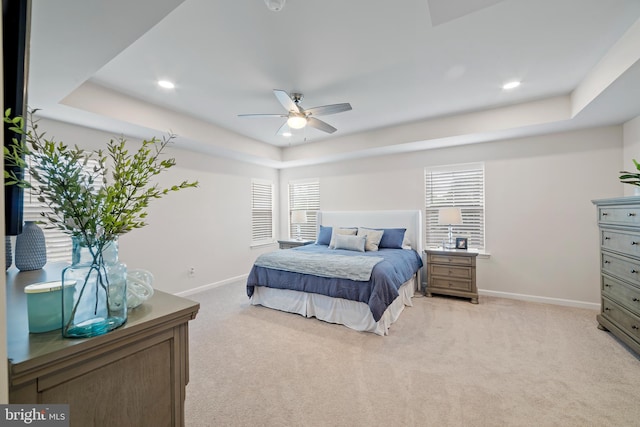 carpeted bedroom with ceiling fan and a tray ceiling