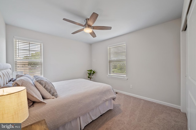 carpeted bedroom featuring multiple windows, ceiling fan, and a closet