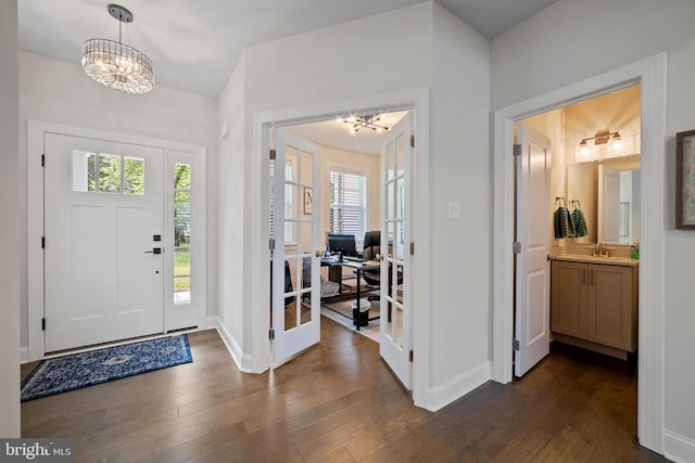 foyer featuring dark wood-type flooring, an inviting chandelier, and a healthy amount of sunlight