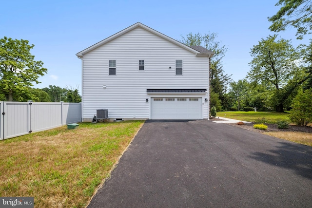 view of home's exterior with central AC, a garage, and a lawn