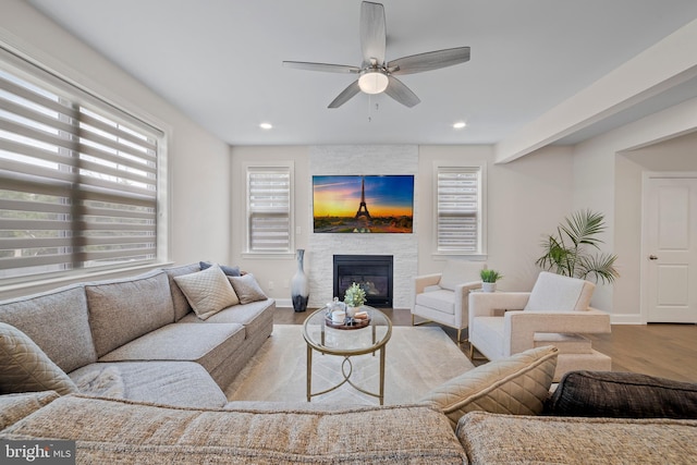 living room with ceiling fan, a healthy amount of sunlight, light wood-type flooring, and a fireplace