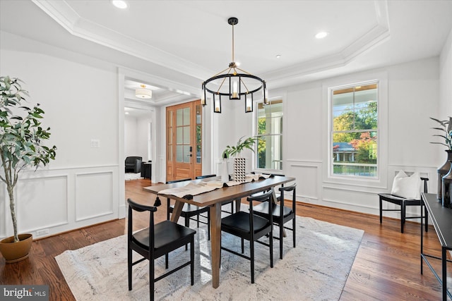 dining space featuring a chandelier, ornamental molding, light hardwood / wood-style floors, and a tray ceiling