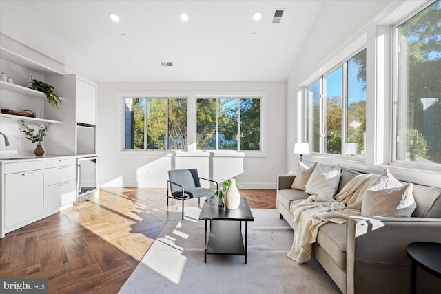 living room with a wealth of natural light, light parquet floors, beverage cooler, and vaulted ceiling