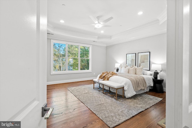 bedroom featuring dark hardwood / wood-style floors, a raised ceiling, ceiling fan, and crown molding