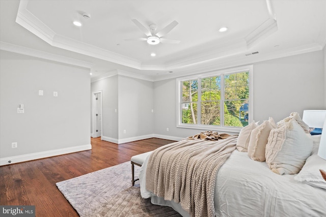 bedroom with a tray ceiling, ceiling fan, dark wood-type flooring, and ornamental molding