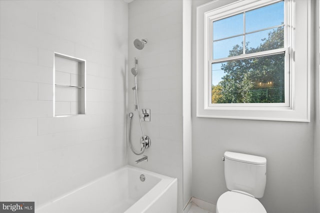 bathroom featuring plenty of natural light, toilet, and tiled shower / bath