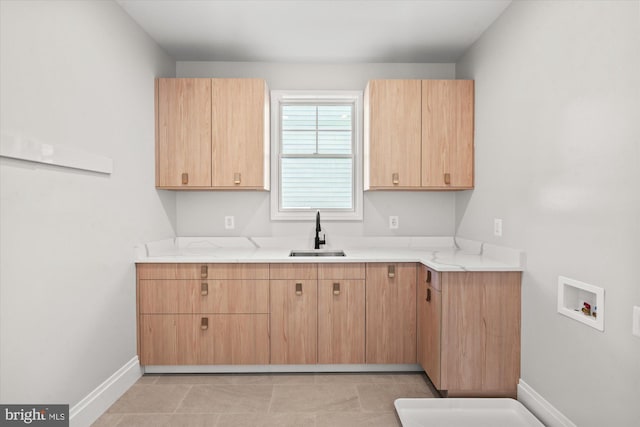 kitchen featuring light brown cabinets, light stone counters, light tile patterned floors, and sink