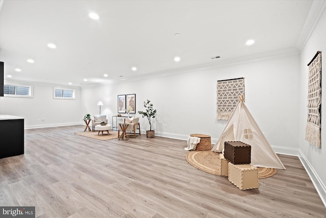 game room with ornamental molding and light hardwood / wood-style flooring