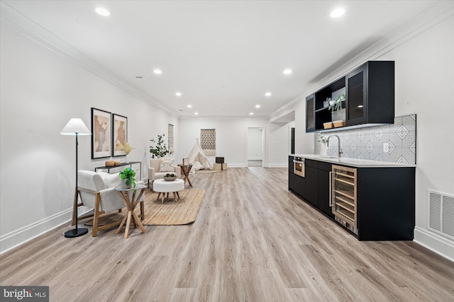 kitchen with wine cooler, light hardwood / wood-style flooring, ornamental molding, and sink