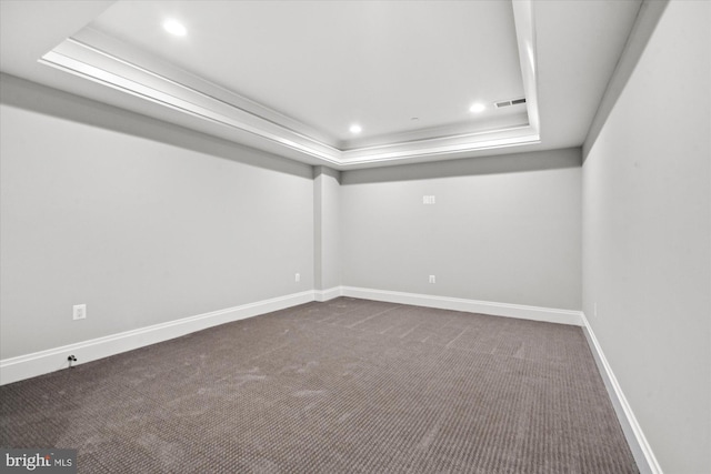 carpeted empty room featuring a raised ceiling