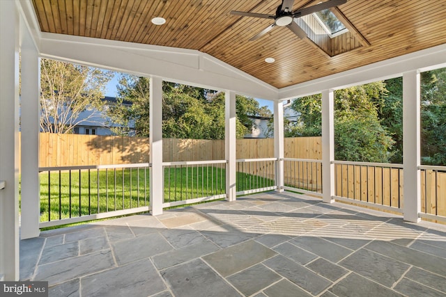 unfurnished sunroom with ceiling fan, wood ceiling, and vaulted ceiling with skylight