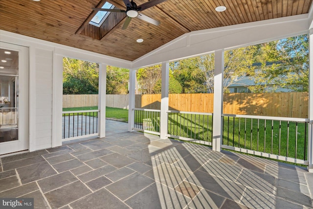 unfurnished sunroom with ceiling fan, wood ceiling, and vaulted ceiling with skylight